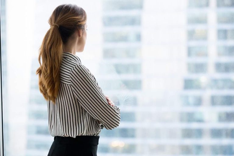 Rear view at confident rich businesswoman looking forward through window